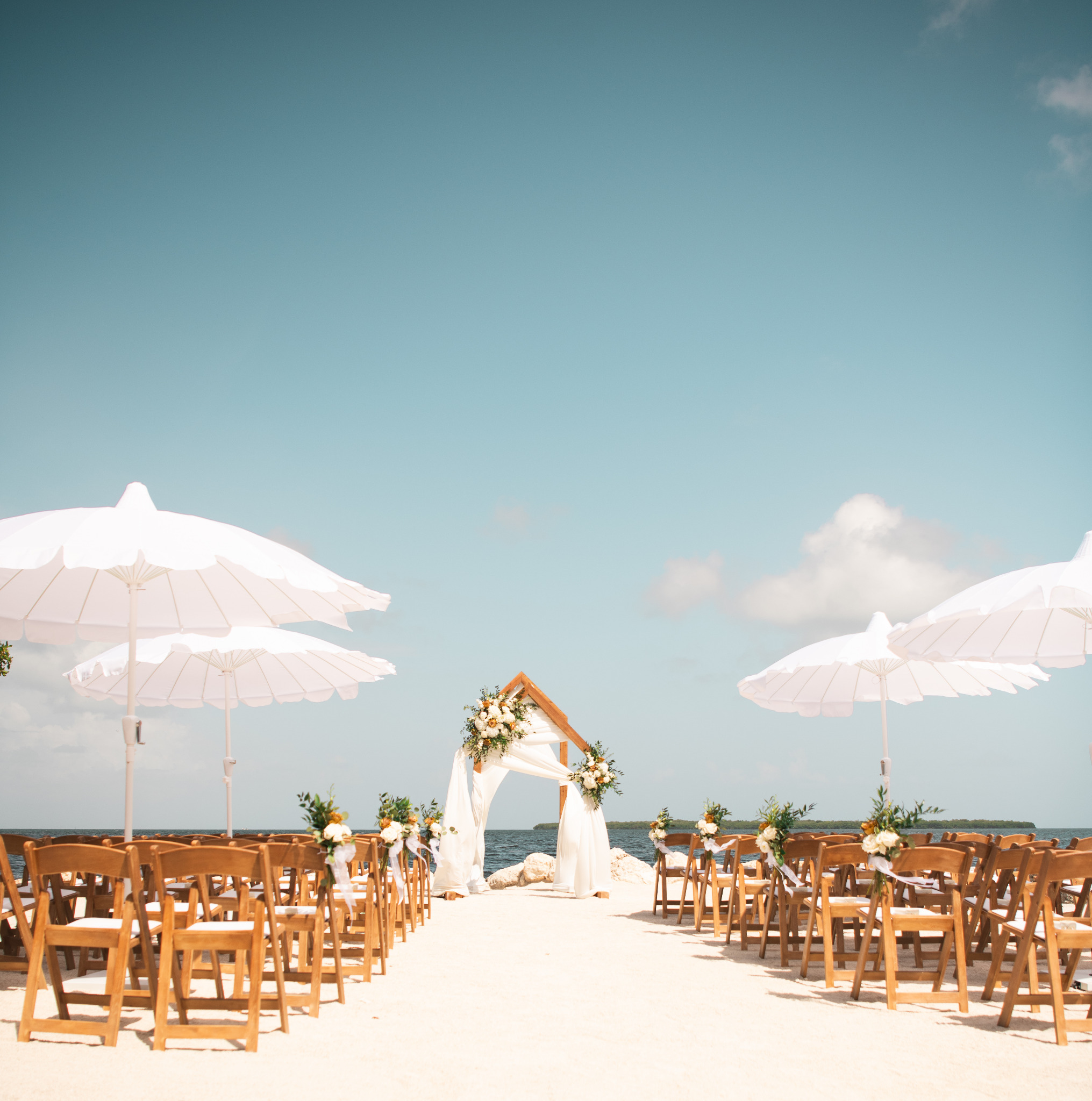 Waterfront wedding ceremony with Cart Haus umbrellas and wedding arch