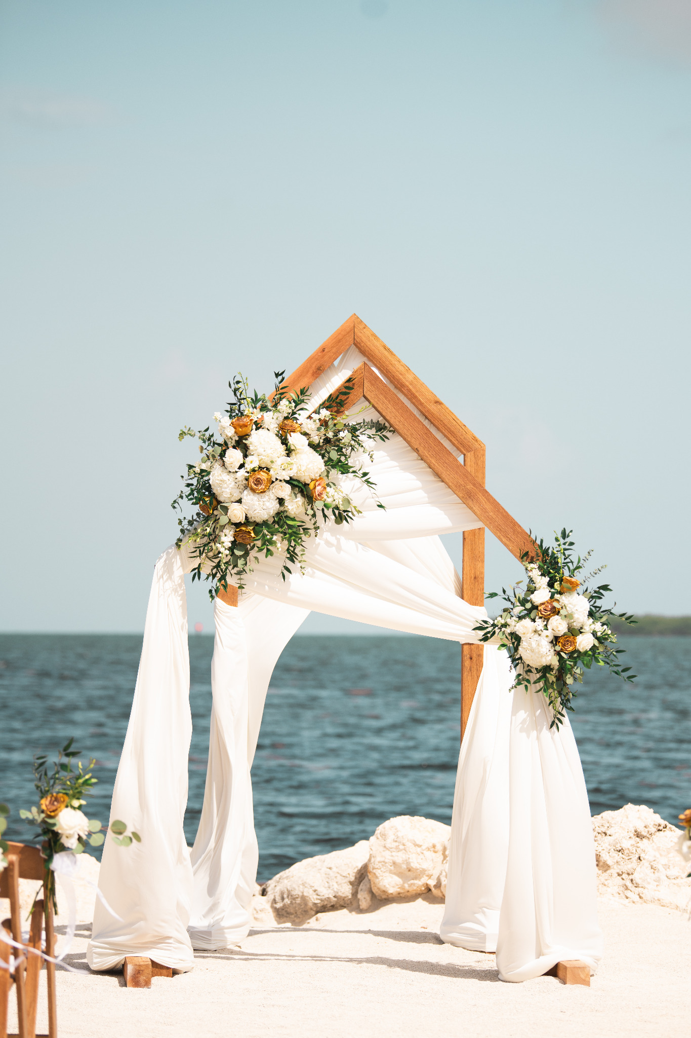 Waterfront wedding arch with florals and draping